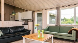 Un salón acogedor con un sofá de cuero negro, un sofá verde y una mesa de centro de madera con jarrones.