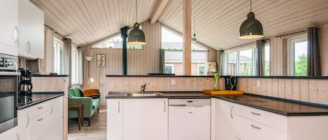 Una cocina moderna con vigas de madera, armarios blancos y una isla central.