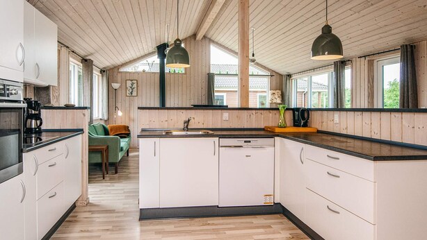 Una cocina moderna con vigas de madera, armarios blancos y encimeras negras.