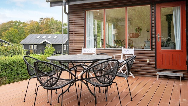 A wooden house with a large window and a deck with outdoor furniture. - 6 Person Holiday Home in Børkop (Borkop)