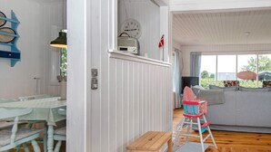 A room with a dining table and chairs, a wooden stool, a sofa, and a television. - 6 Person Holiday Home in Børkop (Borkop)