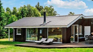 Uma casa moderna com um terraço amplo, uma chaminé e uma porta de vidro que dá para um pátio.