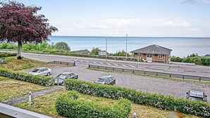 Una strada costiera con un’area di parcheggio, un piccolo edificio e un albero.