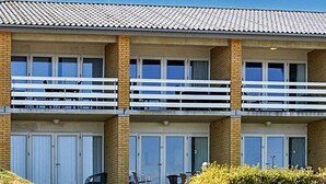 Un hotel a più piani con balconi, ampie finestre e tetto piano.