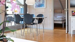 A room with a dining table, chairs, a bed, a TV, and a painting on the wall.
