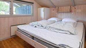 A bedroom with a bunk bed, wooden walls, a window, and a red lamp.
