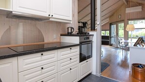 A modern kitchen with white cabinetry, a black countertop, a stove, and a coffee maker.