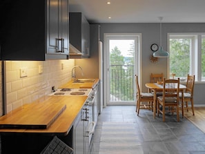 A modern kitchen with a wooden countertop, stainless steel appliances, and a dining area with wooden chairs and a table. - Holiday Home in HenÃ¥n (Henån)