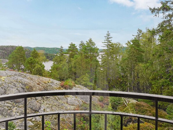 A scenic overlook with a metal railing, a rocky hillside, and a forested valley with a river in the distance. - Holiday Home in HenÃ¥n (Henån)