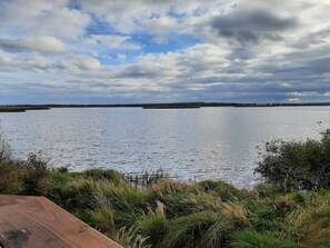 A calm lake with a wooden deck in the foreground and a distant shoreline.