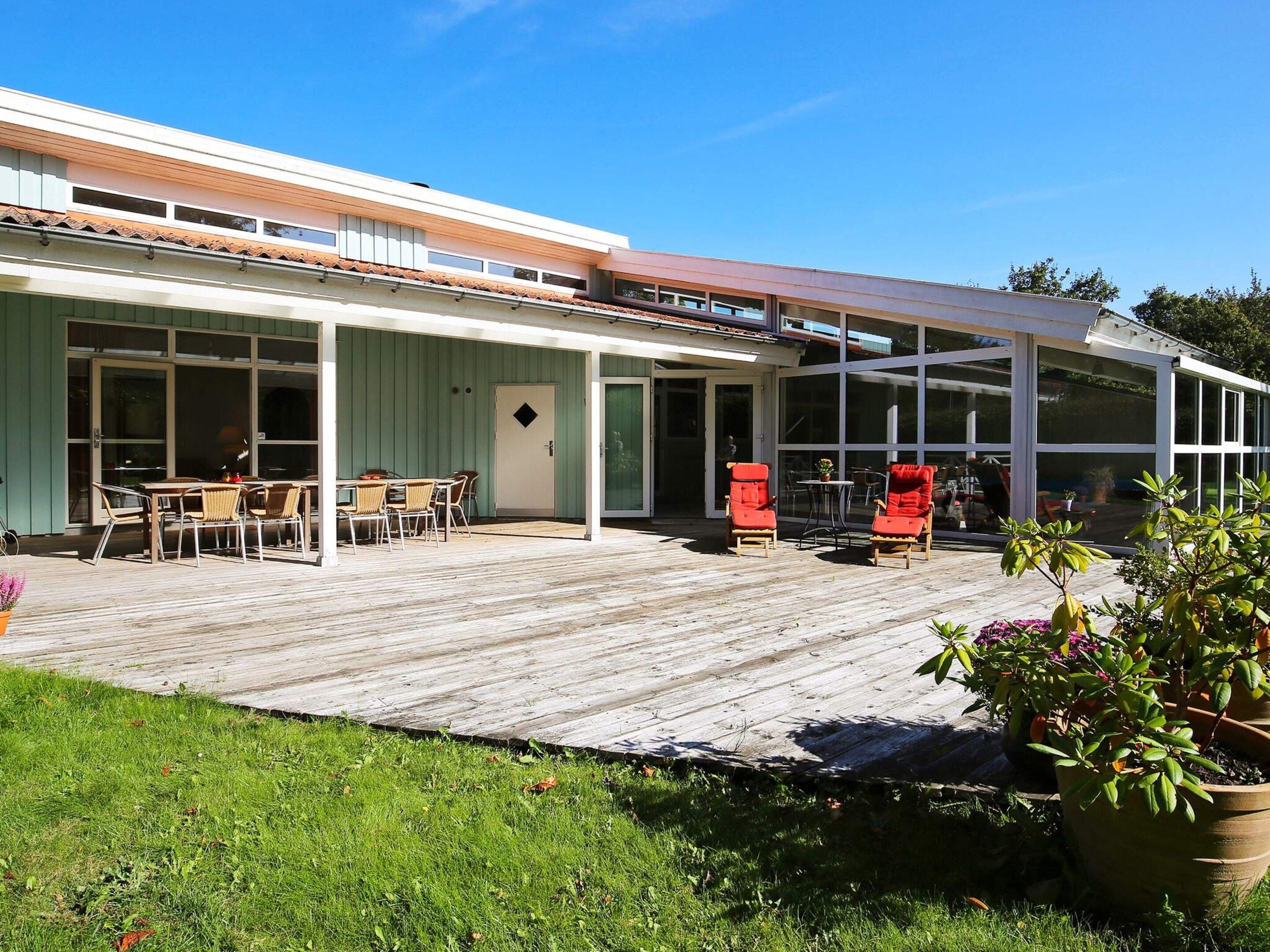 Una casa moderna con un porche cubierto, un comedor y una amplia sección con ventanales.