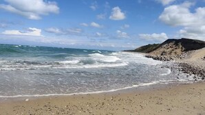 Une plage avec des vagues, un ciel dégagé et un promontoire rocheux.