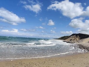 A beach with waves, a clear sky, and a rocky outcrop. - Holiday Home in Tisvildeleje (Tisvildeleje)