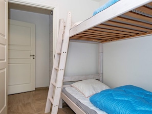 A bunk bed with a wooden ladder, a white door, and a blue blanket. - Holiday Home in Holstebro (Holstebro)