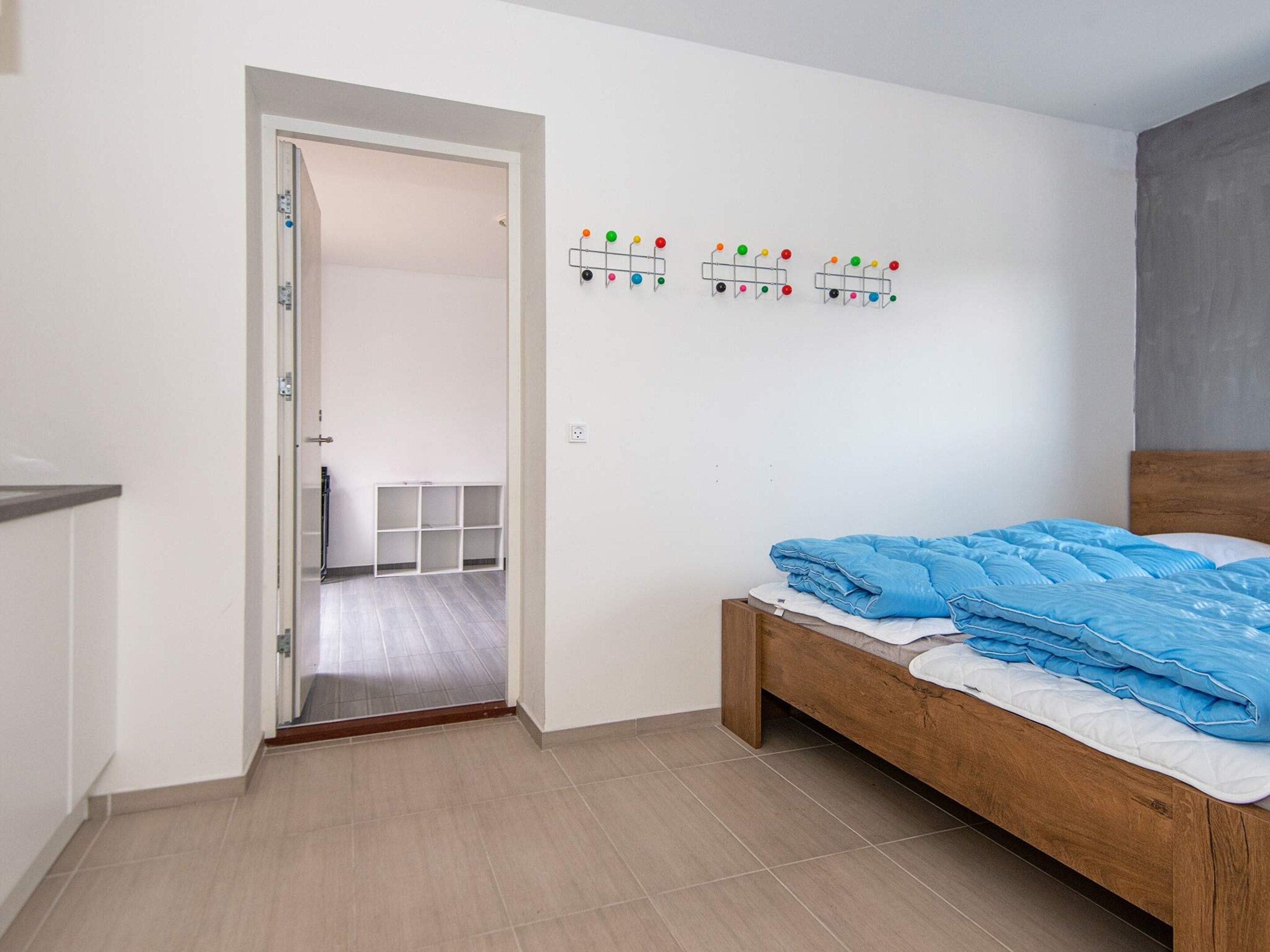 A bedroom with a wooden bed, a white door, and a wall-mounted light switch.
