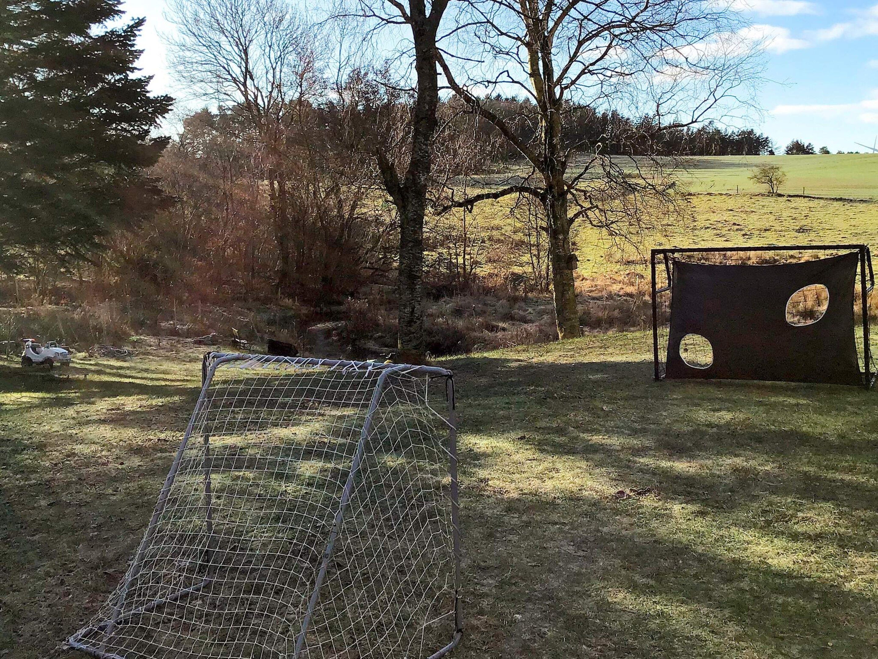 A fenced area with a wire enclosure and a wooden structure with circular cutouts.