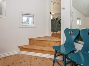A room with a wooden staircase, a blue chair, and a window with a view of a building outside.