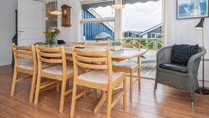 A dining area with wooden chairs and a table, a clock, and a framed picture on the wall. - Holiday Home in Juelsminde (Horsens)