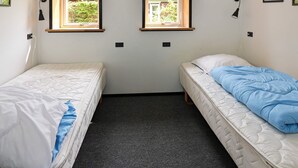 A small room with two single beds, a carpeted floor, and two windows with wooden frames. - 6 Person Holiday Home in Hadsund (Hadsund)
