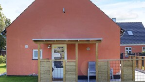 A single-story building with a sloped roof, a covered patio area with a table and chairs, and a small window. - 6 Person Holiday Home in Hadsund (Hadsund)