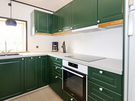 Una cocina moderna con gabinetes verdes, horno empotrado y cafetera.