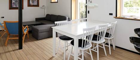 A modern interior with a dining table, chairs, a sofa, and artwork on the walls.