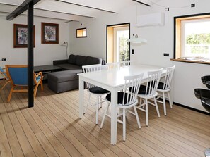 Un interior modern amb una taula de dinar, cadires, un sofà i obra d'art a les parets.