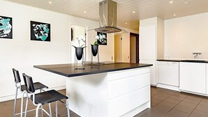 A modern kitchen with a central island, bar stools, and a dishwasher. - 8 Person Holiday Home in Vaeggerlose (Vaeggerlose)