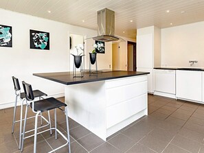 A modern kitchen with a central island, bar stools, and a dishwasher. - 8 Person Holiday Home in Vaeggerlose (Vaeggerlose)