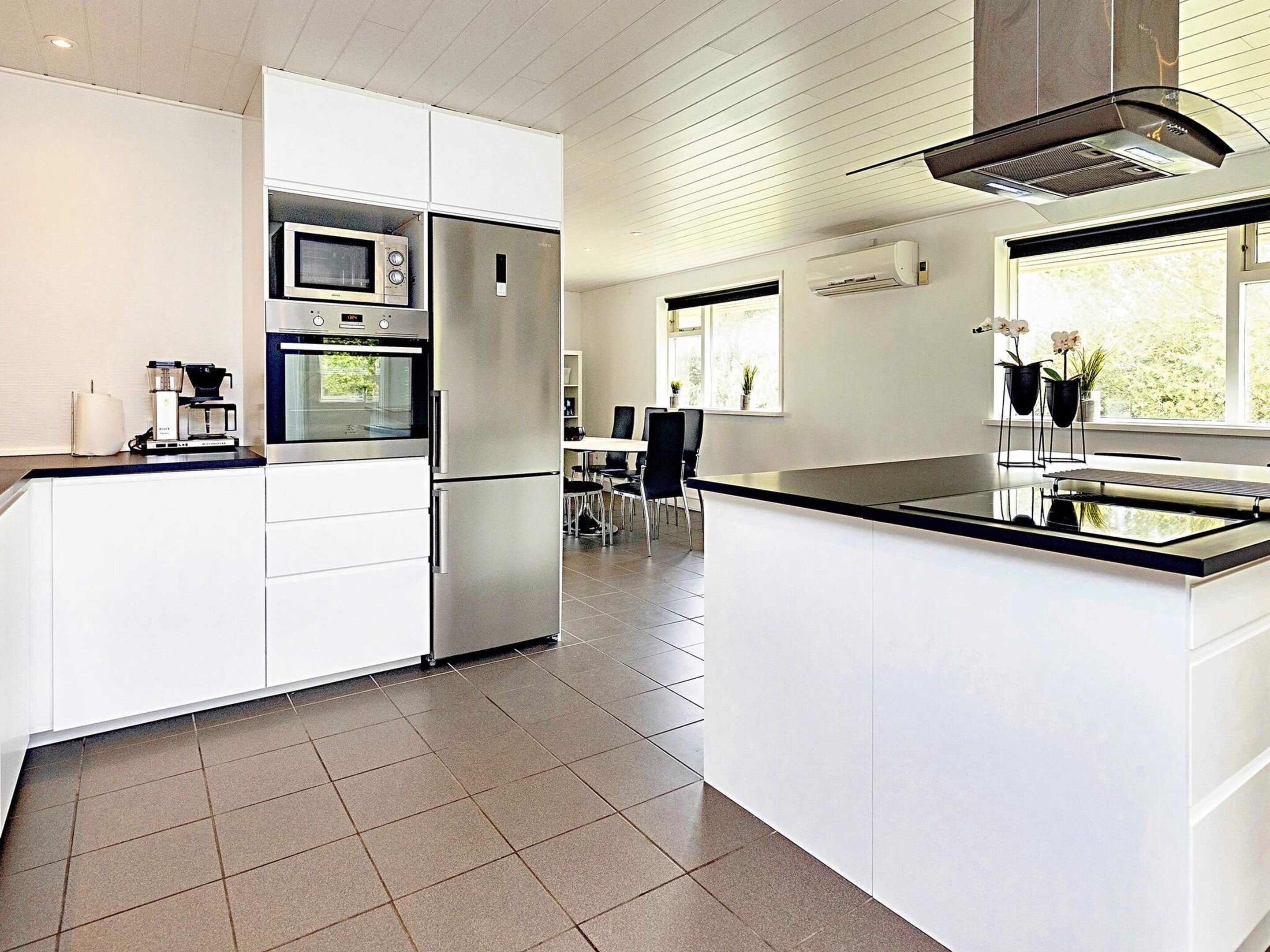A modern kitchen with white cabinetry, stainless steel appliances, and a large island.