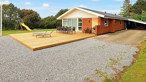 A modern house with a patio, a play area, and a barbecue setup. - 8 Person Holiday Home in Vaeggerlose (Vaeggerlose)