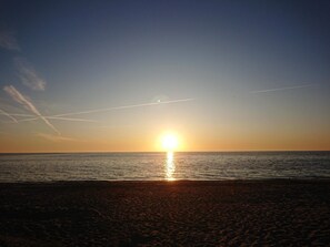 A sunset over a beach with a clear sky and visible contrails. - 8 Person Holiday Home in Vaeggerlose (Vaeggerlose)