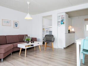 A modern living space with a sofa, a coffee table, a dining area with a chair, and a kitchen area.