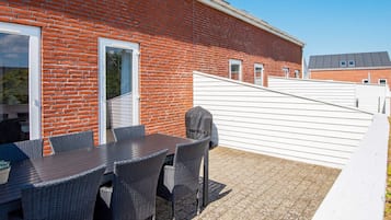 An outdoor patio with a brick wall, a covered table, and chairs.