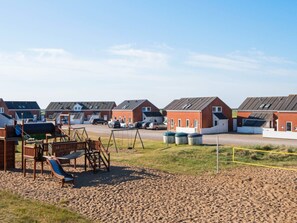 Ein Wohngebiet mit mehreren Häusern, einem Spielplatz und einem Parkplatz.