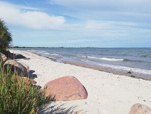 A beach with large rocks, a sandy shore, and waves. - Holiday Home in Sydals (Sydals)