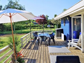 Terraza con mobiliario exterior, una mesa y sillas, rodeada por una barandilla blanca.