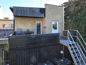 A rooftop terrace with a table and chairs, a small door, and a staircase leading to an upper level. - 4 Person Holiday Home in Skagen (Skagen)