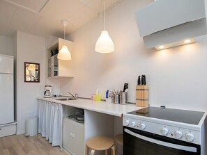 Una cocina compacta con estufa, pileta y lámparas colgantes.
