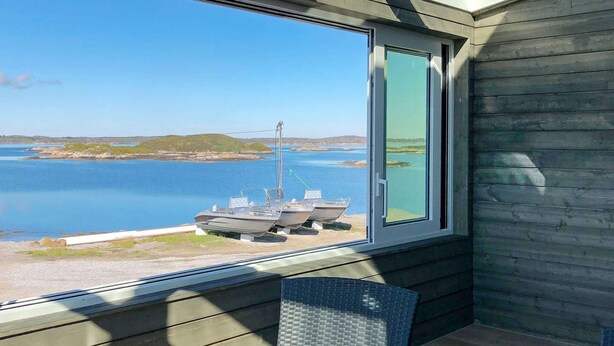 A room with a large window overlooking a body of water, a chair, and a small table. - 6 Person Holiday Home in Dyrvik (Frøya)