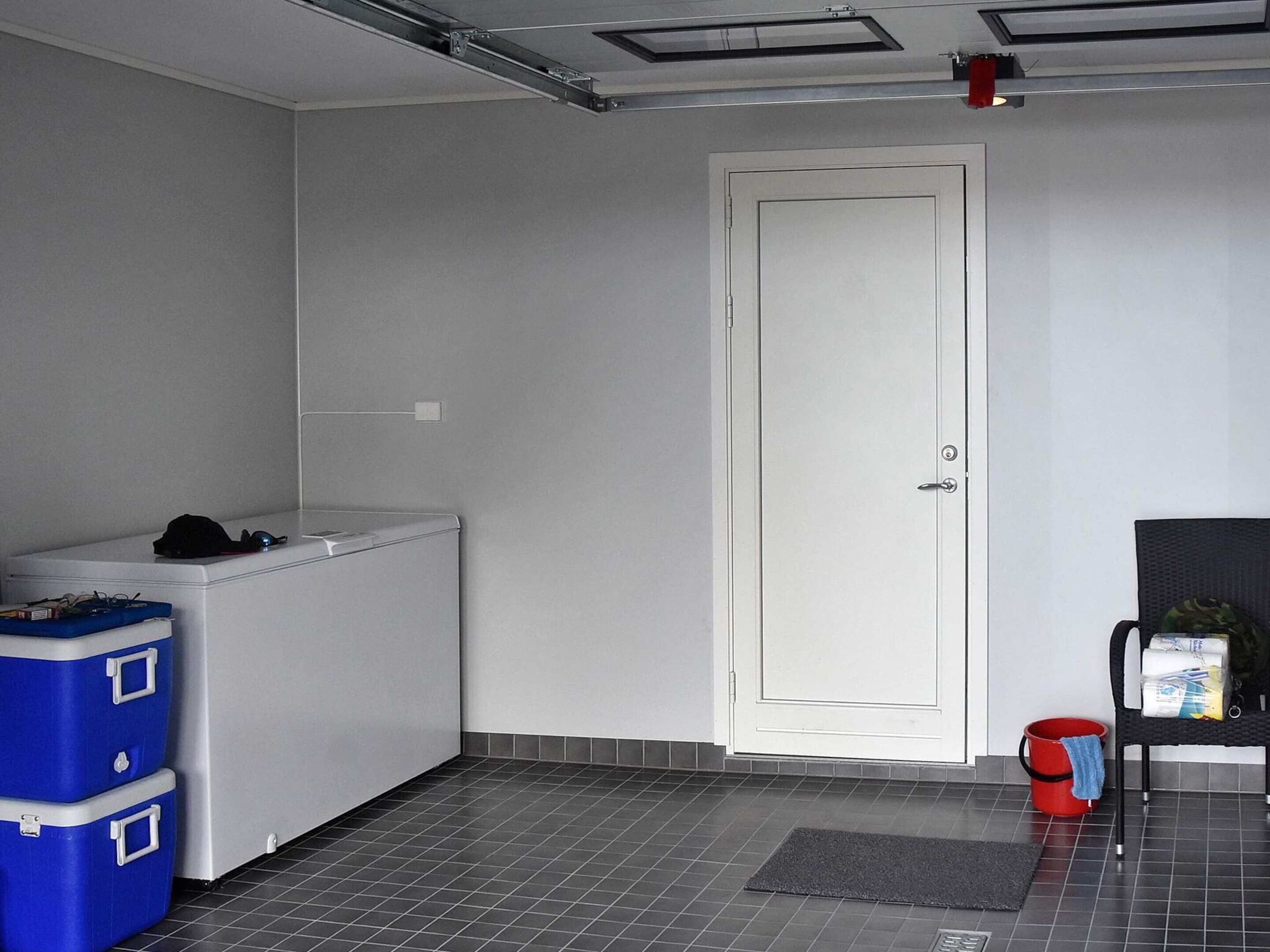 Een kleine wasruimte met een witte deur, een wasmachine en twee blauwe opbergmanden.
