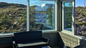 A conservatory with a view of rocky terrain and a distant building. - 6 Person Holiday Home in Dyrvik (Frøya)