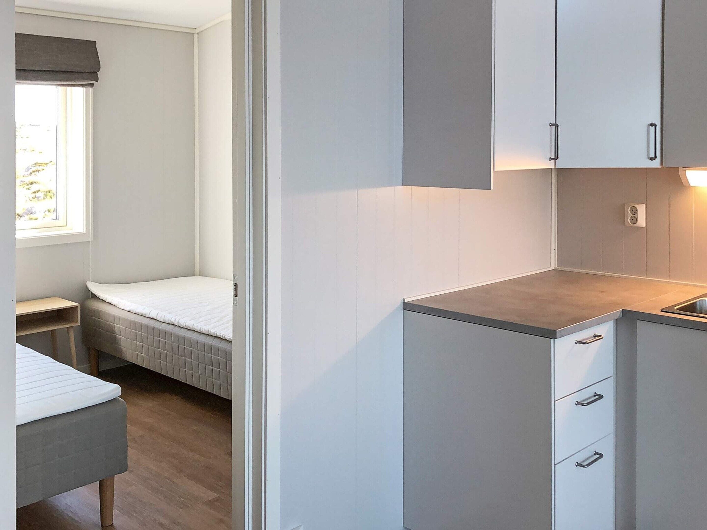 Une chambre compacte et moderne, dotée d’une kitchenette, d’un lit et d’une fenêtre offrant une vue agréable.