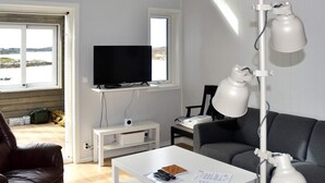 A modern living room with a television, a white coffee table, a grey sofa, and a black armchair. - 6 Person Holiday Home in Dyrvik (Frøya)