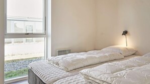 A bedroom with a large window, a bed, a bedside table, and a wall-mounted lamp. - 6 Person Holiday Home in Nexo (Nexø)