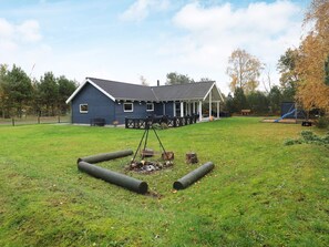 A blue house with a porch and a swing set in a grassy yard.
