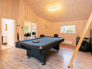 A pool table in a room with wooden walls and a sloped ceiling.