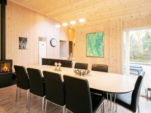Ein Essbereich mit einem langen Tisch, Stühlen, einer Uhr und einem Kamin.