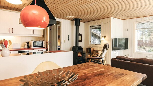 A modern kitchen with wooden cabinets, a central island, and a wood-burning stove. - 3 Person Holiday Home in Albaek (Aalbaek)