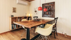 A dining area with a wooden table, two yellow chairs, a red pendant light, and a wall-mounted air conditioner. - 3 Person Holiday Home in Albaek (Aalbaek)
